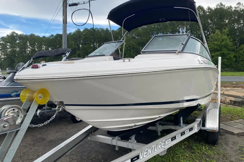 Slide: The Image of 2017 Regal 1900 ES Bowrider on trailer, parked outdoors with trees in background. - 2
