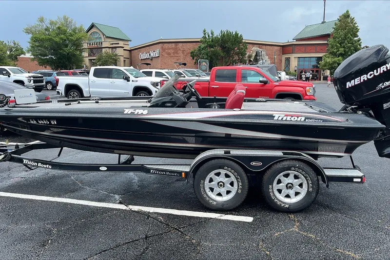 Slide: The Image of 2008 Triton Tr-196 SC boat on trailer in parking lot near outdoor store. - 1