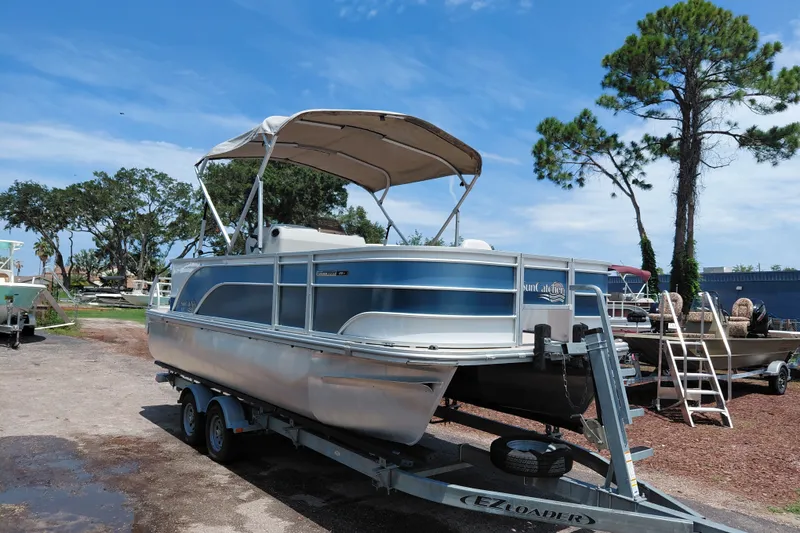 The Image of 2022 SunCatcher Select 20F pontoon boat on trailer, parked outdoors under blue sky. - 1