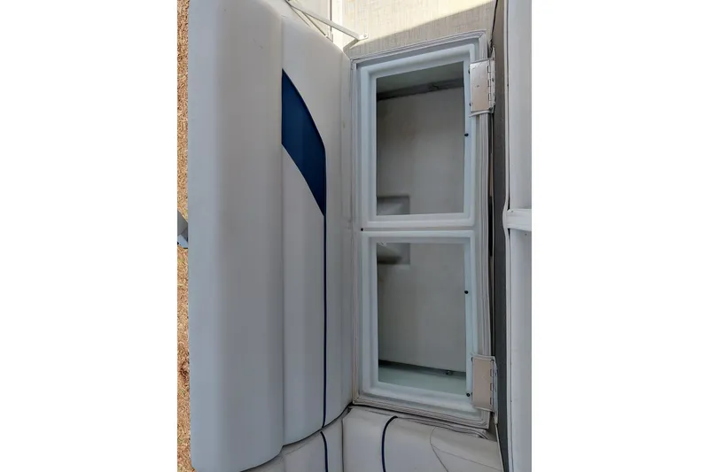 Slide: The Image of Open storage compartment on 2022 SunCatcher Select 20F boat, featuring white interior and blue accents. - 26