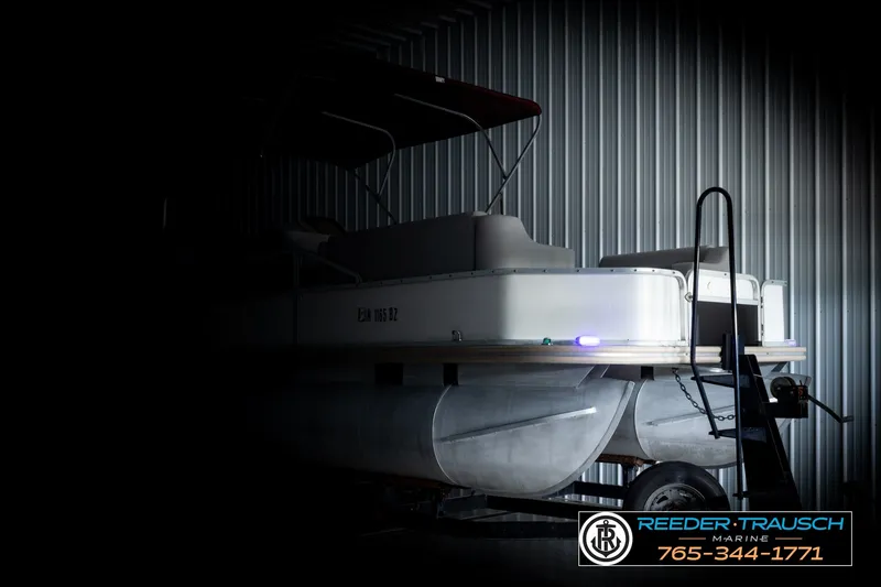 Slide: The Image of 2003 Fisher 220 FISH boat in dimly lit storage, featuring pontoon design. - 4