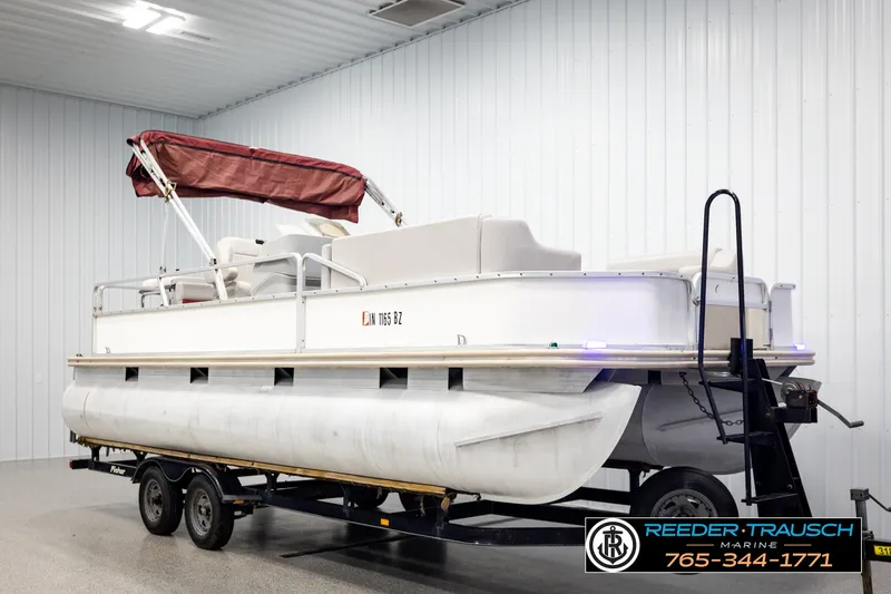 Slide: The Image of 2003 Fisher 220 FISH pontoon boat with maroon canopy on trailer in indoor storage. - 2