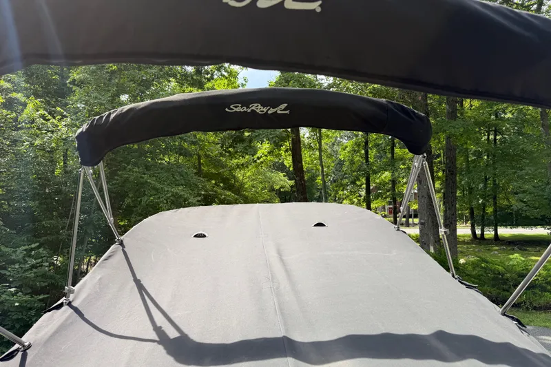 Slide: The Image of 2016 Sea Ray Sundancer 260 boat with canopy, surrounded by lush green trees. - 73