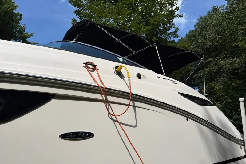 Slide: The Image of 2016 Sea Ray Sundancer 260 boat with canopy, docked outdoors under blue sky. - 13