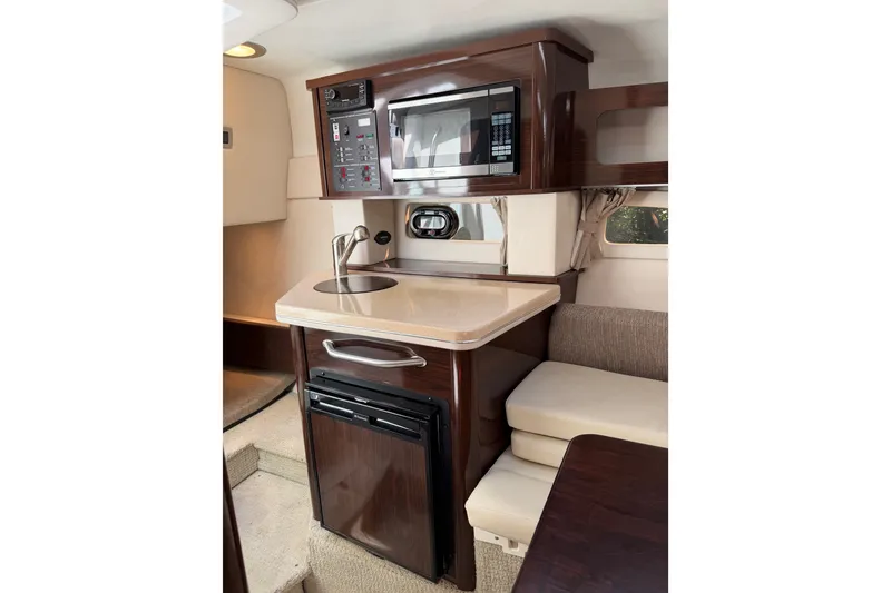 Slide: The Image of 2016 Sea Ray Sundancer 260 cabin interior with kitchenette, featuring microwave, sink, and seating area. - 37