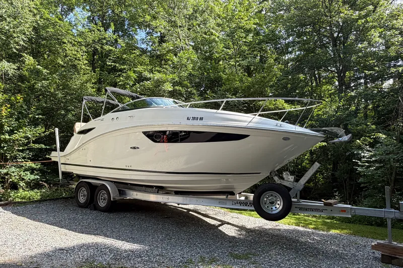 Slide: The Image of 2016 Sea Ray Sundancer 260 boat on trailer, surrounded by lush green trees. - 17