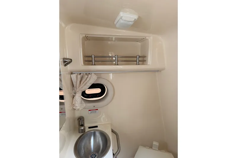 Slide: The Image of 2016 Sea Ray Sundancer 260 bathroom with sink, porthole, and storage shelf. - 54