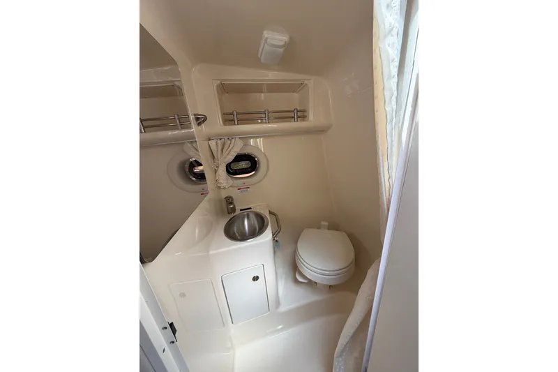 Slide: The Image of 2016 Sea Ray Sundancer 260 bathroom with sink, toilet, and porthole window. - 51
