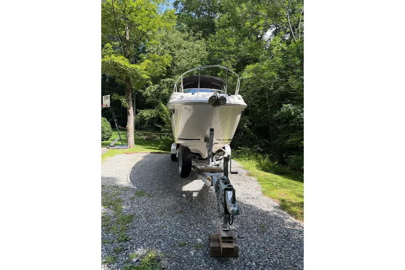 Slide: The Image of 2016 Sea Ray Sundancer 260 on trailer, parked on gravel driveway surrounded by lush greenery. - 8