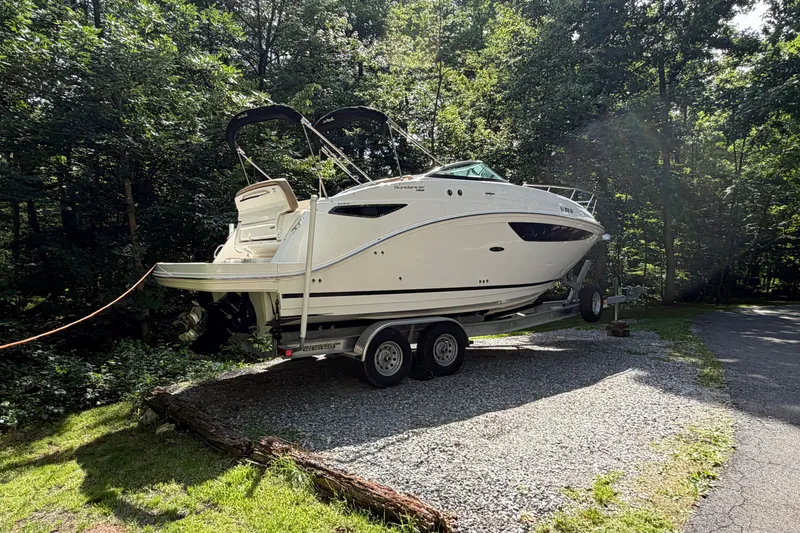 Slide: The Image of 2016 Sea Ray Sundancer 260 boat on trailer, surrounded by lush greenery. - 16
