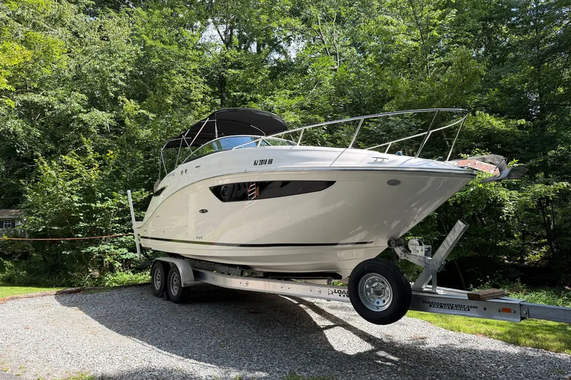 Slide: The Image of 2016 Sea Ray Sundancer 260 boat on trailer, surrounded by lush greenery. - 1