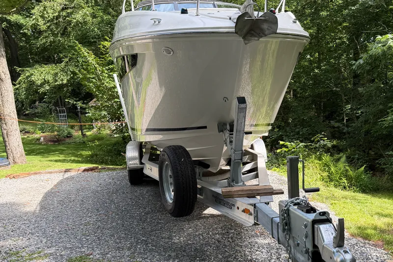 Slide: The Image of 2016 Sea Ray Sundancer 260 boat on trailer, parked on gravel driveway surrounded by greenery. - 22