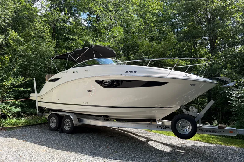 Slide: The Image of 2016 Sea Ray Sundancer 260 boat on trailer, surrounded by lush green trees. - 11