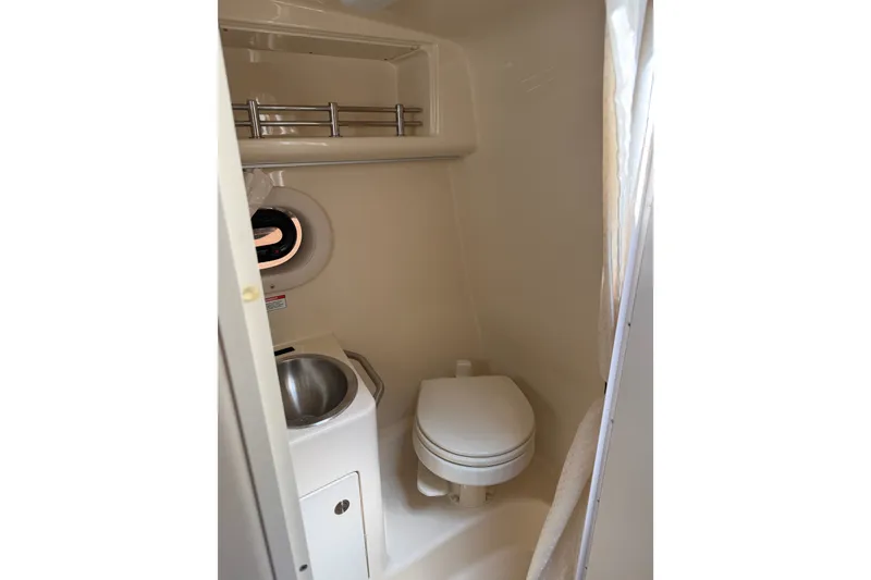 Slide: The Image of 2016 Sea Ray Sundancer 260 bathroom with toilet, sink, and porthole window. - 55