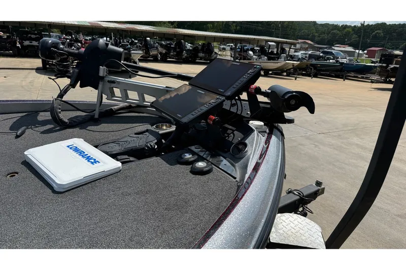 Slide: The Image of 2024 Triton 21 TrX Patriot boat with Lowrance electronics on deck, parked outdoors. - 10