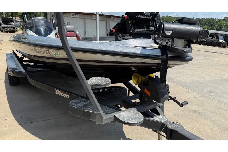 Slide: The Image of 2024 Triton 21 TrX Patriot boat on trailer, featuring Lowrance equipment, parked outdoors. - 11
