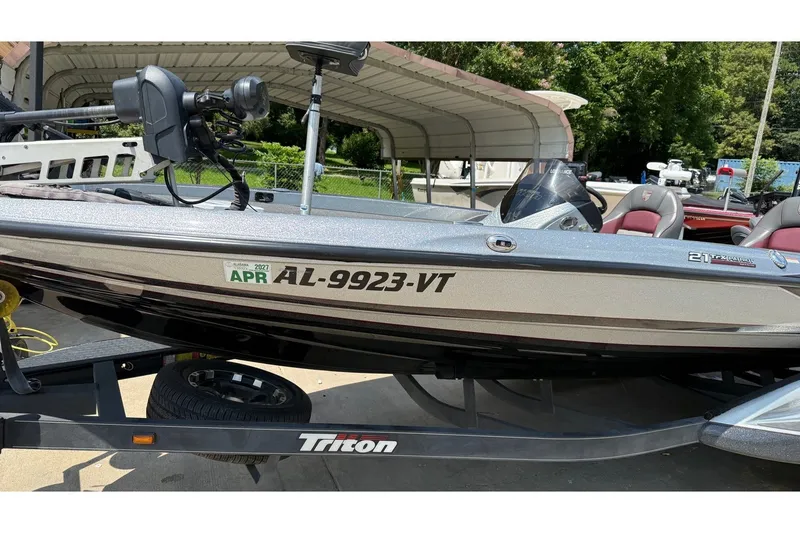 Slide: The Image of 2024 Triton 21 TrX Patriot boat on trailer, side view with registration number visible. - 12
