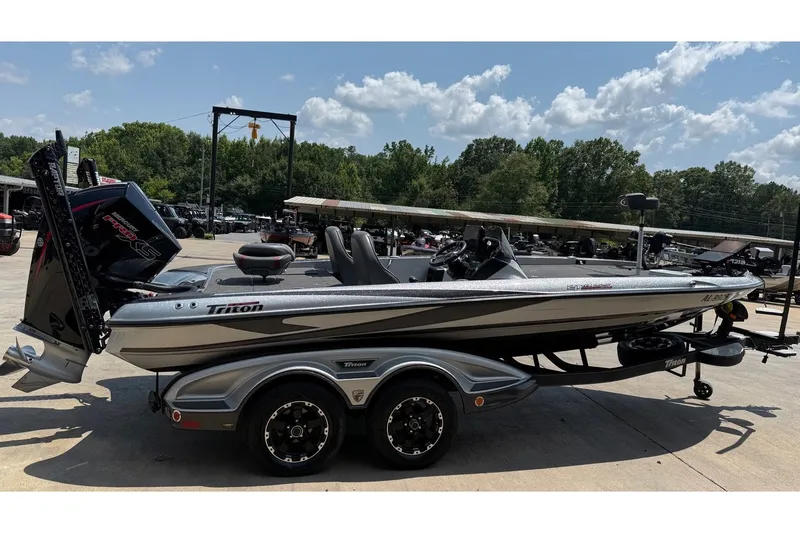 Slide: The Image of 2024 Triton 21 TrX Patriot boat on trailer, parked outdoors under a sunny sky. - 7