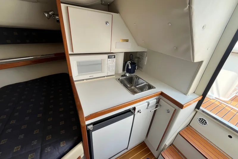 Slide: The Image of 2001 Tiara Yachts 2900 Coronet interior with kitchenette, featuring sink, microwave, and compact fridge. - 26