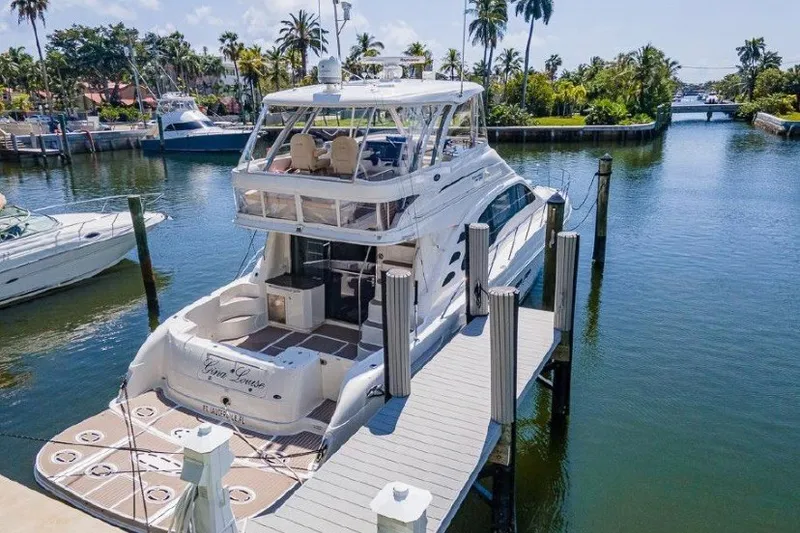 Slide: The Image of 2013 Sea Ray 580 Sedan Bridge yacht docked in a scenic marina with palm trees. - 2