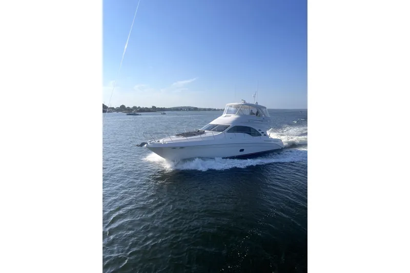 Slide: The Image of 2013 Sea Ray 580 Sedan Bridge yacht cruising on open water under clear blue sky. - 1