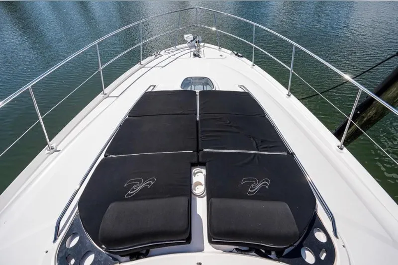 Slide: The Image of 2013 Sea Ray 580 Sedan Bridge yacht bow with black sun pads on calm water. - 3