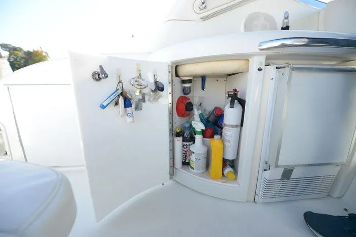 Slide: The Image of Open storage cabinet on 2007 Formula 34 PC boat, containing keys and cleaning supplies. - 18