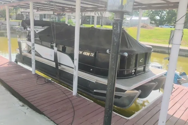 Slide: The Image of 2023 Crest Classic DLX 220 pontoon boat docked under a covered slip. - 1