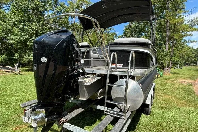 Slide: The Image of 2023 Crest Classic DLX 220 pontoon boat on trailer, featuring powerful outboard motor. - 21