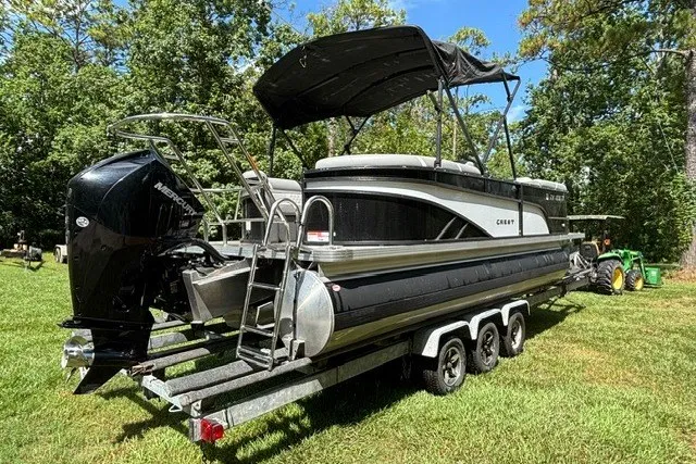 Slide: The Image of 2023 Crest Classic DLX 220 pontoon boat on trailer, parked on grass. - 19