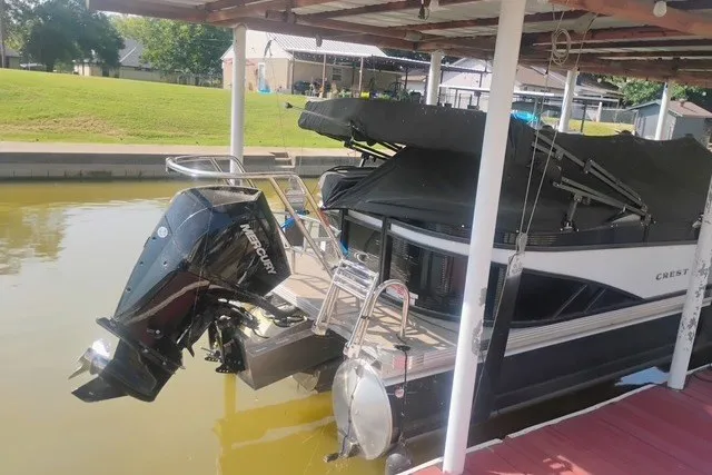 Slide: The Image of 2023 Crest Classic DLX 220 pontoon boat docked with Mercury outboard motor. - 2