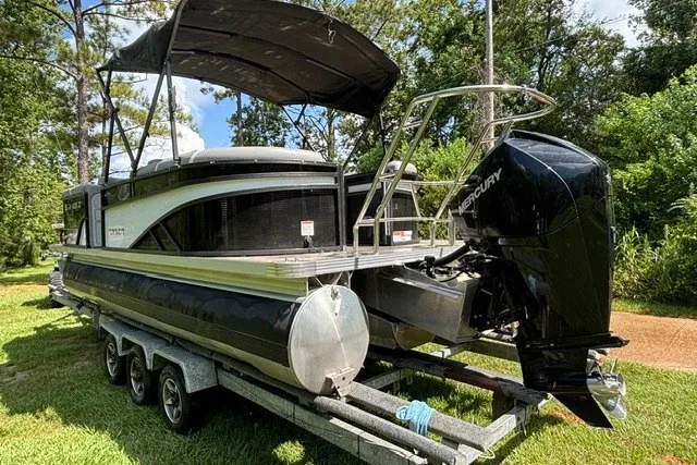 Slide: The Image of 2023 Crest Classic DLX 220 pontoon boat on trailer, surrounded by lush greenery. - 18