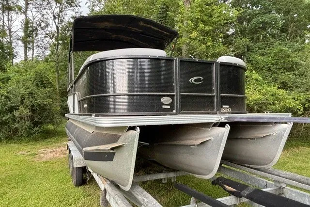Slide: The Image of 2023 Crest Classic DLX 220 pontoon boat on trailer, surrounded by lush greenery. - 6