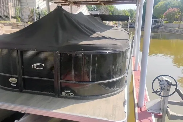 Slide: The Image of 2023 Crest Classic DLX 220 pontoon boat docked with cover, side view. - 3