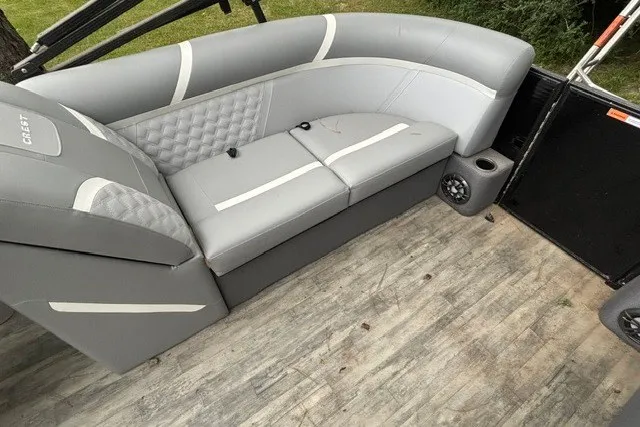 Slide: The Image of 2023 Crest Classic DLX 220 boat interior with gray seating and wood-style flooring. - 12