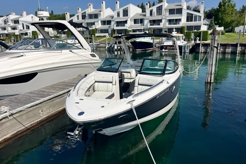Slide: The Image of 2023 Regal LS6 boat docked at marina with modern waterfront homes in background. - 1