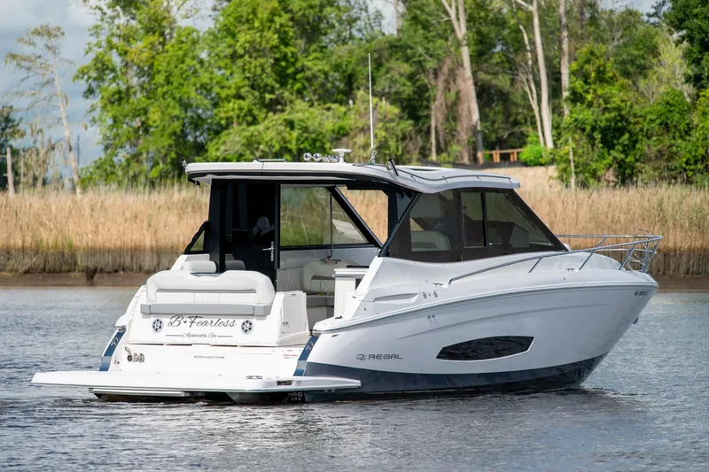 Slide: The Image of 2025 Regal 36 Grande Coupe luxury boat on a serene waterway, surrounded by lush greenery. - 3