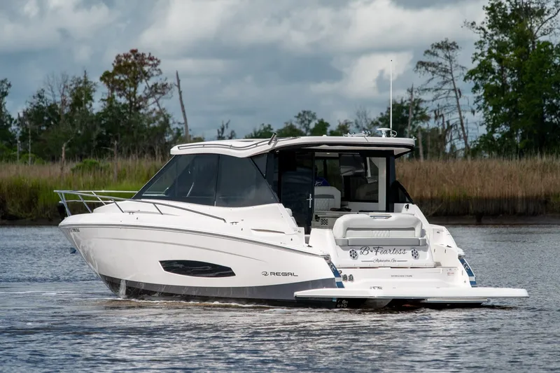 Slide: The Image of 2025 Regal 36 Grande Coupe cruising on a serene river with lush greenery. - 5