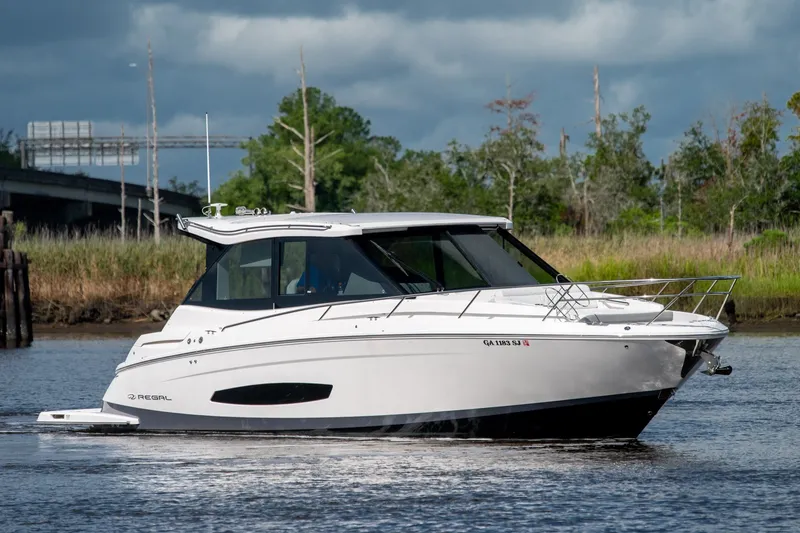 Slide: The Image of 2025 Regal 36 Grande Coupe cruising on a serene river with lush greenery. - 10
