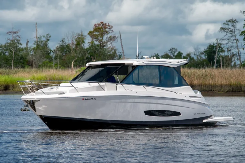 Slide: The Image of 2025 Regal 36 Grande Coupe cruising on a serene lake with lush greenery in the background. - 8