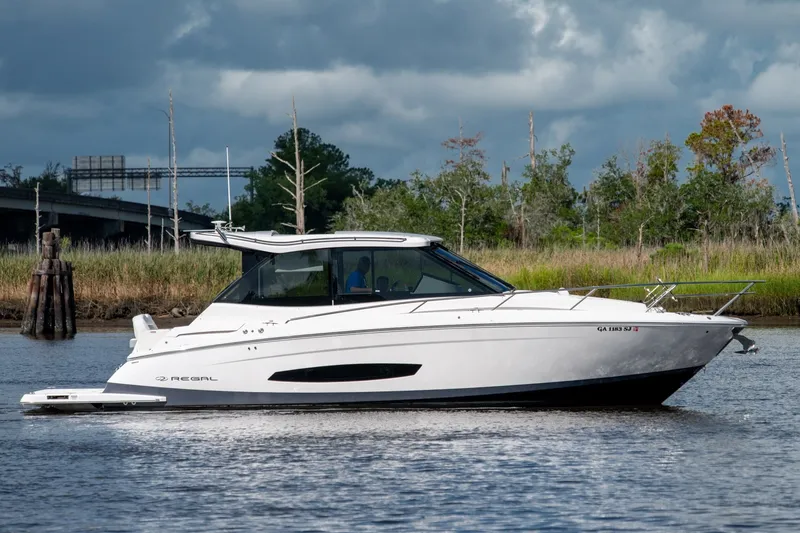 Slide: The Image of 2025 Regal 36 Grande Coupe cruising on a serene river with lush greenery. - 11