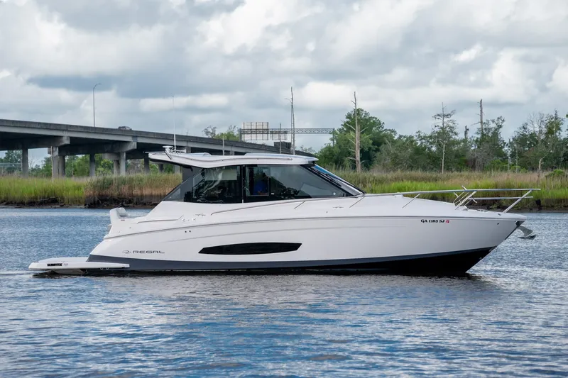 Slide: The Image of 2025 Regal 36 Grande Coupe cruising on a serene river under a cloudy sky. - 1