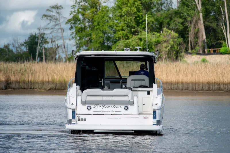 Slide: The Image of 2025 Regal 36 Grande Coupe boat cruising on a calm river with lush greenery. - 4