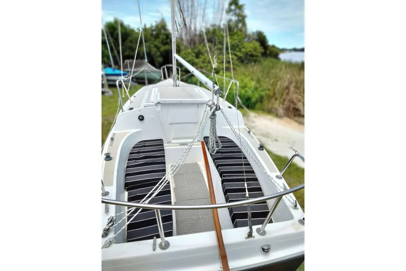 Slide: The Image of 1980 MacGregor 25 sailboat deck with rigging, docked near lush greenery. - 8