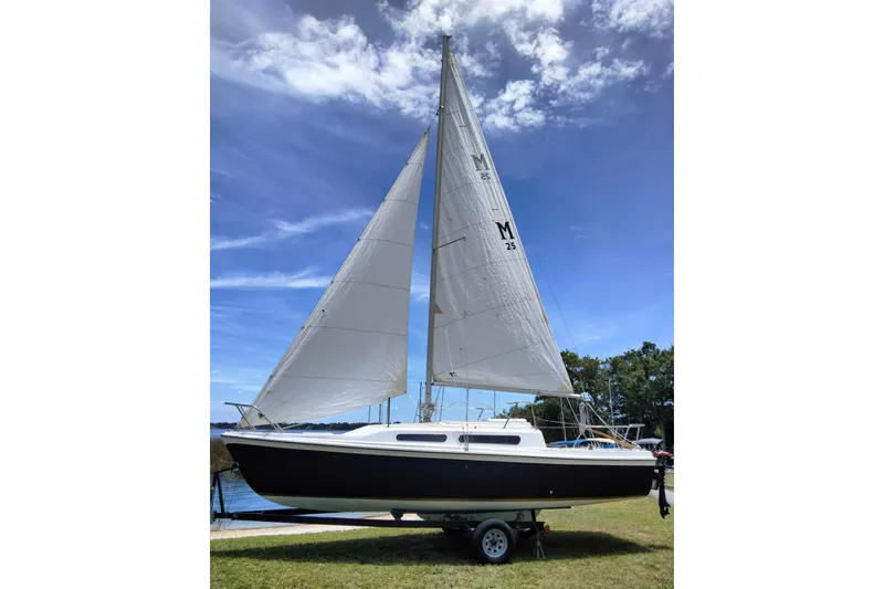 Slide: The Image of 1980 MacGregor 25 sailboat on trailer, set against a clear blue sky. - 4