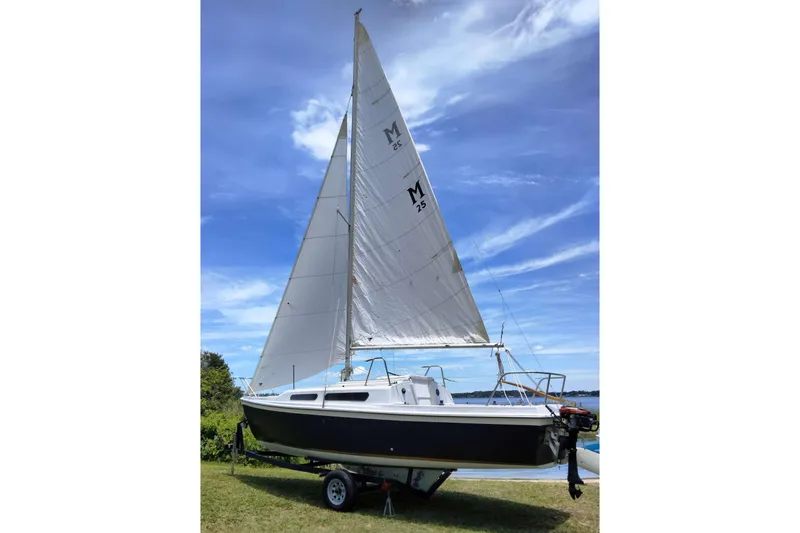 Slide: The Image of 1980 MacGregor 25 sailboat on trailer, set against a clear blue sky. - 3
