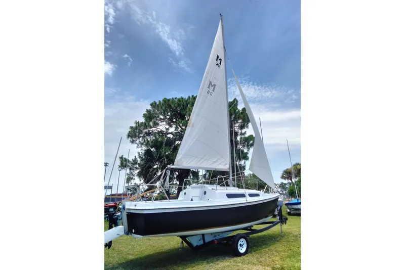 Slide: The Image of 1980 MacGregor 25 sailboat on trailer, set against a clear sky and trees. - 2
