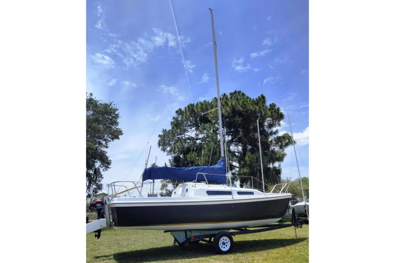 Slide: The Image of 1980 MacGregor 25 sailboat on trailer, set against a clear blue sky and trees. - 6