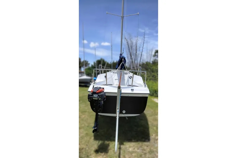 Slide: The Image of 1980 MacGregor 25 sailboat with outboard motor on grassy area under blue sky. - 7