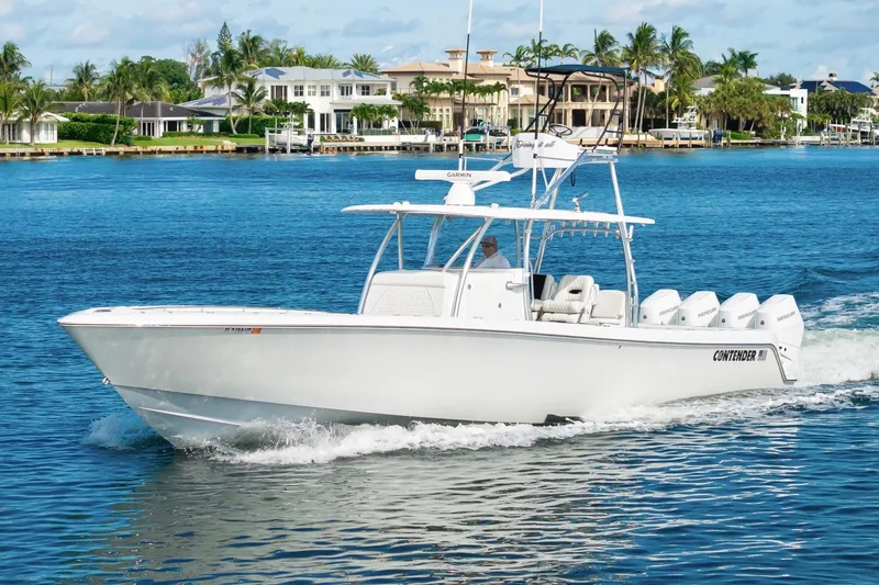 Slide: The Image of 2026 Contender 44 ST boat cruising on a sunny waterfront with luxury homes. - 2